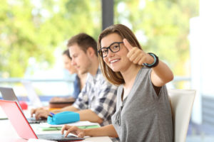teen student with thumbs up in class
